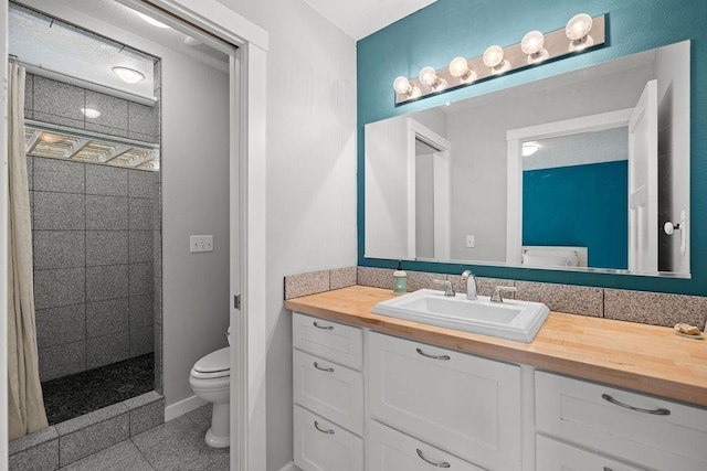 bathroom with toilet, a tile shower, vanity, and baseboards