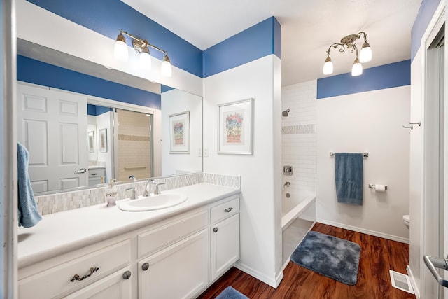 bathroom with toilet, vanity, wood finished floors, washtub / shower combination, and baseboards