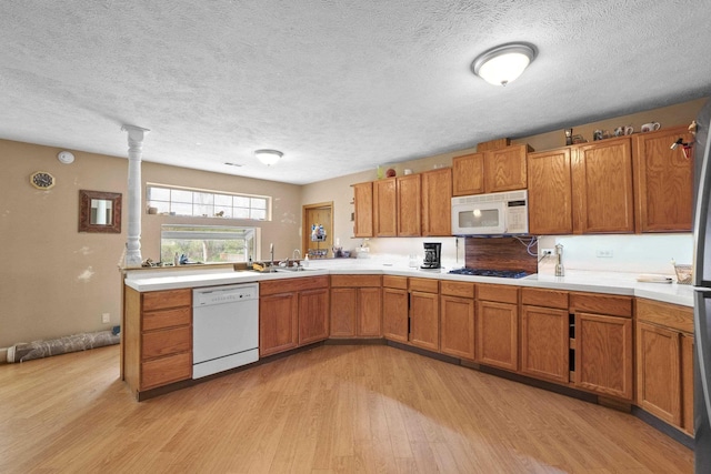 14203 E Belmont Rd, Mica, WA 99023 - kitchen featuring white appliances, light wood-type flooring, brown cabinetry, light countertops, and a textured ceiling