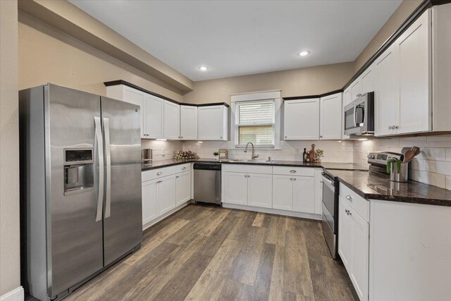 1721 E 12th Ave, Spokane, WA 99202 - kitchen featuring appliances with stainless steel finishes, dark wood finished floors, a sink, backsplash, and white cabinetry