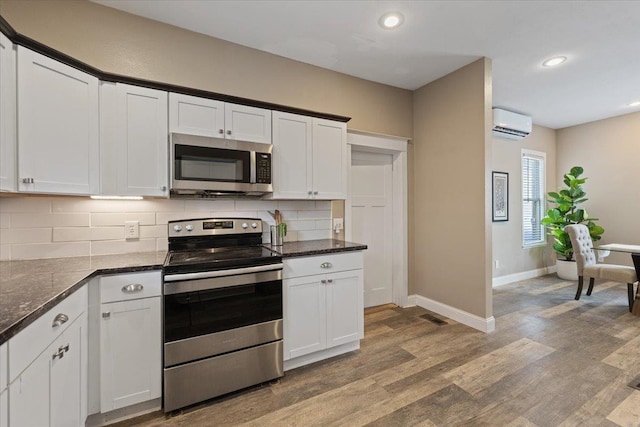 1721 E 12th Ave, Spokane, WA 99202 - kitchen with stainless steel appliances, a wall unit AC, light wood-style flooring, backsplash, and baseboards