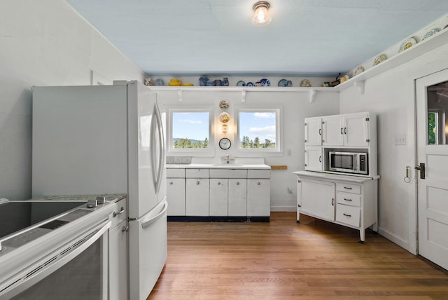 8310 E Belair Rd, Valleyford, WA 99036 - kitchen featuring stainless steel microwave, wood finished floors, electric range oven, white cabinetry, and a sink