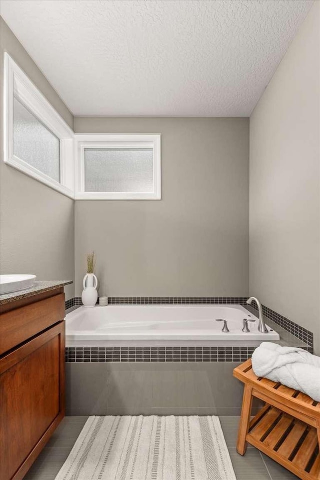 7708 N Warren Ln, Spokane, WA 99208 - bathroom featuring a garden tub, a textured ceiling, vanity, and tile patterned floors