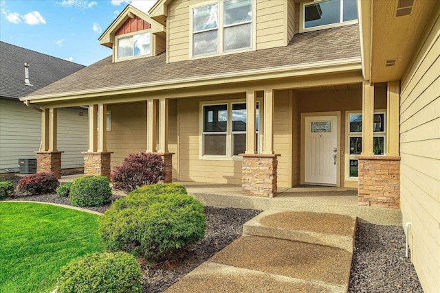 7708 N Warren Ln, Spokane, WA 99208 - view of exterior entry featuring covered porch, roof with shingles, central AC unit, and stone siding