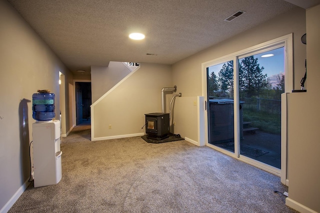 38821 N Newport Hwy, Elk, WA 99009 - empty room featuring a wood stove, carpet floors, a textured ceiling, and baseboards