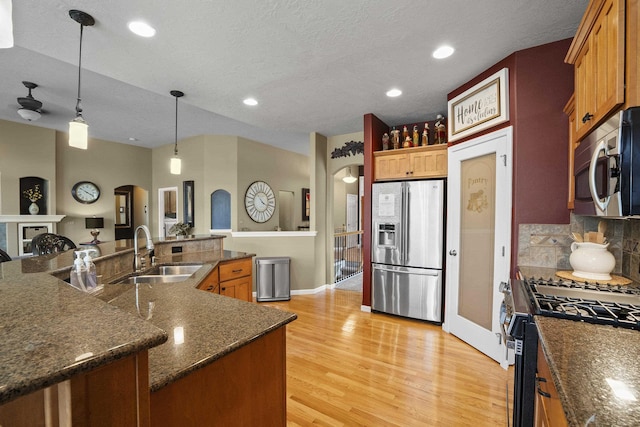 17702 E Galaxy Rd, Greenacres, WA 99016 - kitchen with stainless steel appliances, a sink, arched walkways, decorative backsplash, and light wood-type flooring