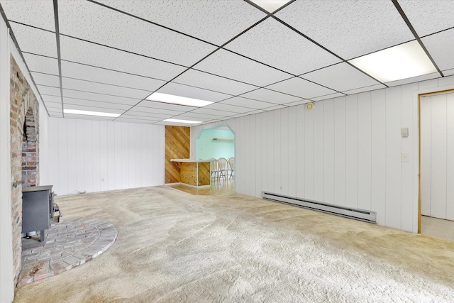 13227 N E Newman Lake Dr, Newman Lake, WA 99025 - basement with a baseboard heating unit, carpet floors, a wood stove, a paneled ceiling, and wood walls
