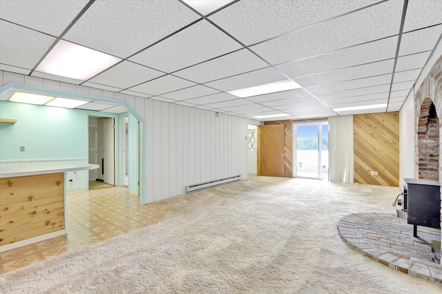 13227 N E Newman Lake Dr, Newman Lake, WA 99025 - unfurnished living room featuring a baseboard radiator, a wood stove, wooden walls, a paneled ceiling, and carpet