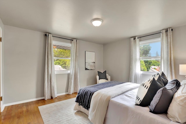 bedroom featuring multiple windows, light wood-style flooring, and baseboards