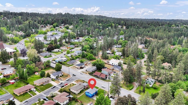 aerial view of property and surrounding area with a forest and nearby suburban area