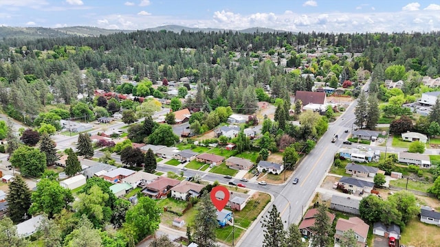 aerial overview of property's location featuring a forest, nearby suburban area, and a mountainous background