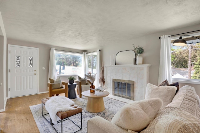 living area featuring a textured ceiling, wood-type flooring, a fireplace, and baseboards