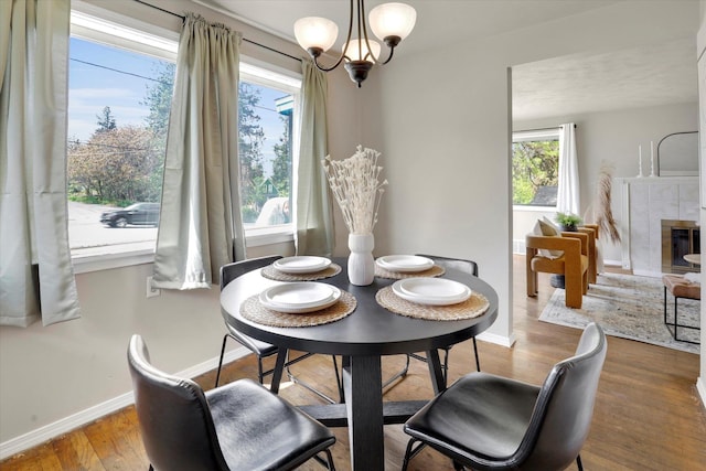 dining area featuring plenty of natural light, baseboards, wood finished floors, and a tile fireplace
