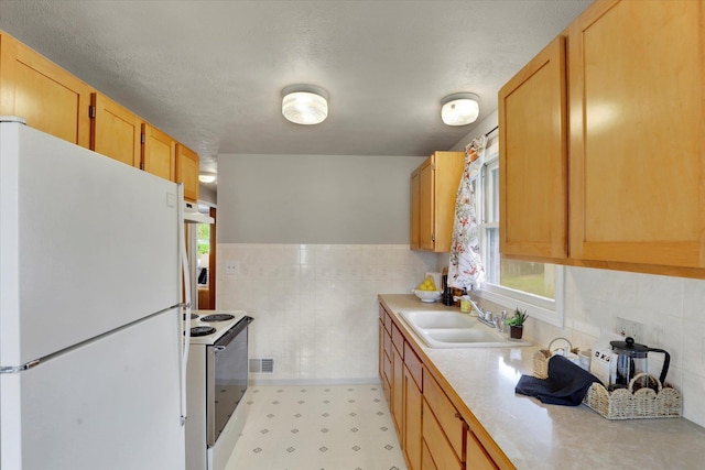 kitchen featuring white appliances, tile walls, light countertops, a sink, and healthy amount of natural light