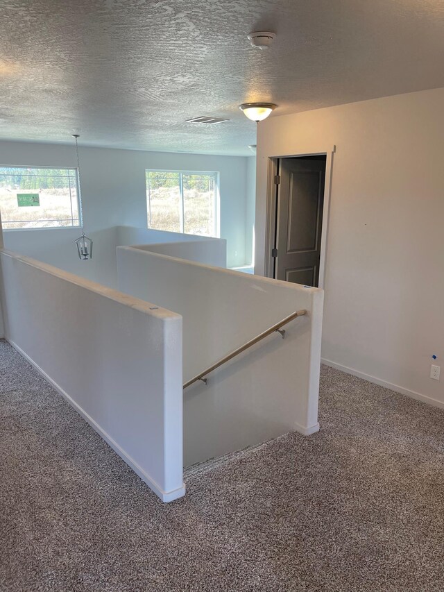 18718 E Riverside Ct, Spokane Valley, WA 99016 - corridor featuring an upstairs landing, carpet floors, plenty of natural light, a textured ceiling, and baseboards