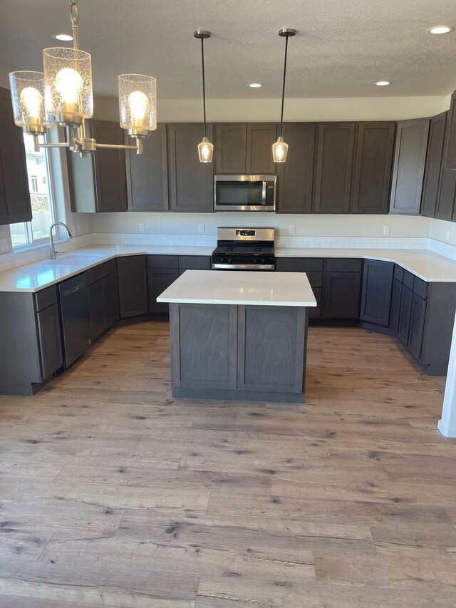 18718 E Riverside Ct, Spokane Valley, WA 99016 - kitchen with appliances with stainless steel finishes, a chandelier, light wood finished floors, a center island, and recessed lighting