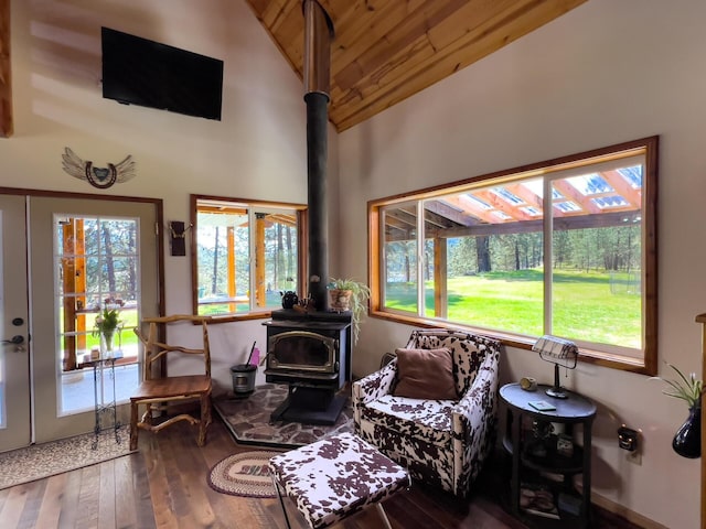 living area featuring a wood stove, vaulted ceiling, wood-type flooring, and wood ceiling