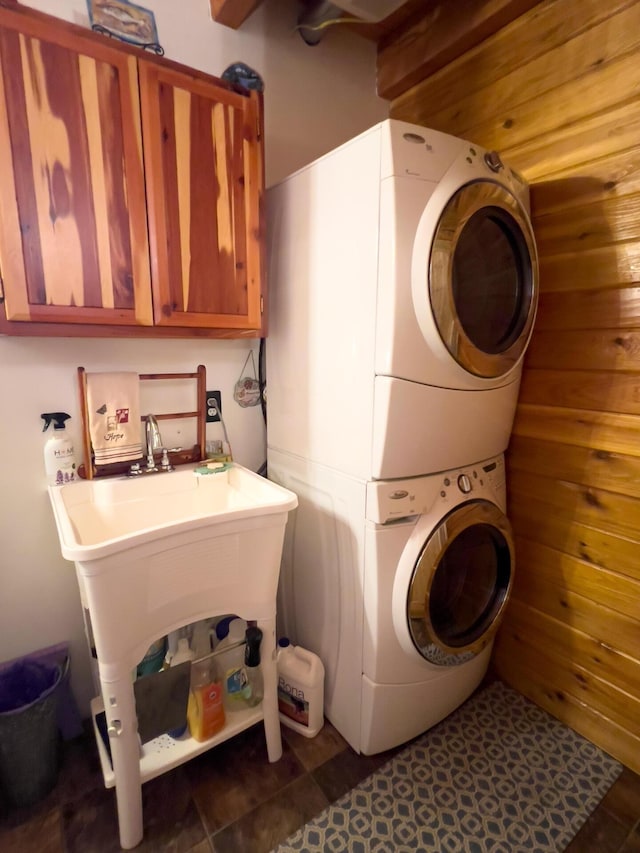 laundry area with estacked washer and dryer and tile patterned floors