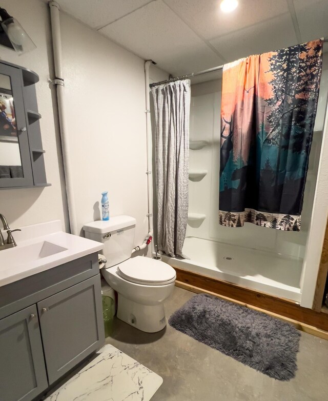 20 River Ranch Rd, Kettle Falls, WA 99141 - bathroom featuring toilet, vanity, finished concrete flooring, a shower with shower curtain, and a paneled ceiling