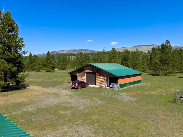 view of outbuilding featuring a mountain view, an outdoor structure, and a view of trees