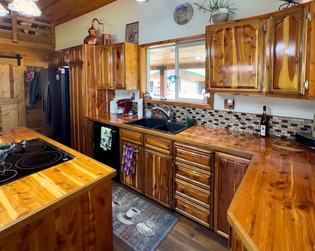 kitchen featuring wood counters, black appliances, a sink, decorative backsplash, and brown cabinetry