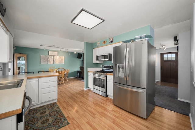 24005 E Garland Ave, Otis Orchards, WA 99027 - kitchen featuring appliances with stainless steel finishes, track lighting, a sink, white cabinetry, and light wood-style floors