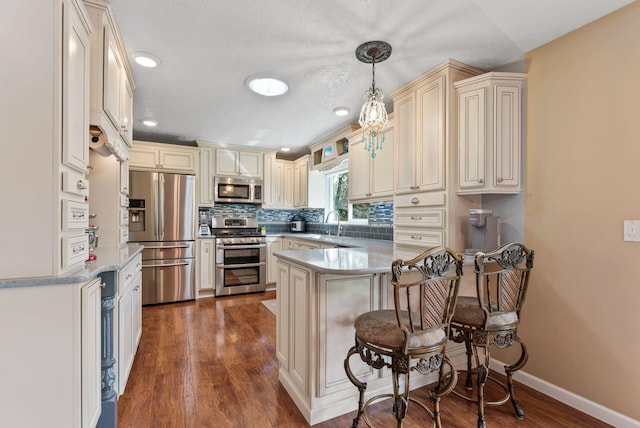 4109 S Hollow Ct, Spokane, WA 99206 - kitchen featuring stainless steel appliances, cream cabinetry, a peninsula, decorative backsplash, and recessed lighting