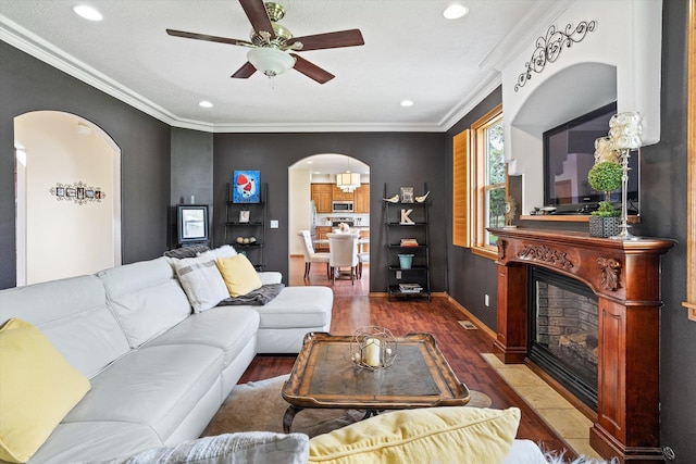 6482 Lakeview Dr, Nine Mile Falls, WA 99026 - living room with arched walkways, wood finished floors, a fireplace with flush hearth, ceiling fan, and ornamental molding