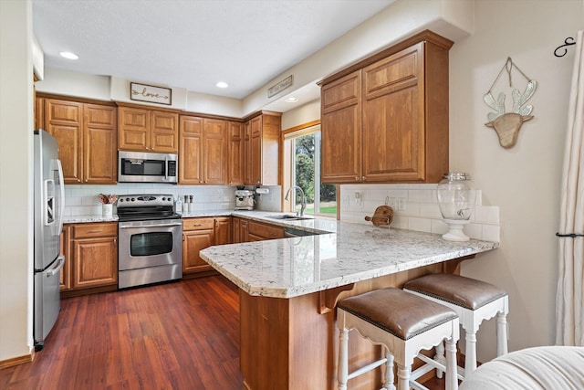 6482 Lakeview Dr, Nine Mile Falls, WA 99026 - kitchen with stainless steel appliances, a peninsula, a sink, brown cabinets, and decorative backsplash