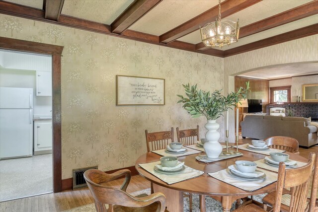 10228 N Whitworth Dr, Spokane, WA 99218 - dining area featuring light wood-type flooring, beam ceiling, a chandelier, wallpapered walls, and arched walkways