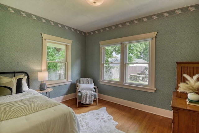 bedroom featuring multiple windows, wood finished floors, and baseboards