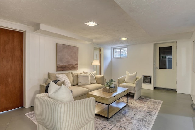 living area featuring heating unit, finished concrete floors, and a textured ceiling