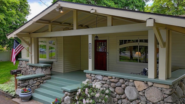 property entrance with a porch and stone siding