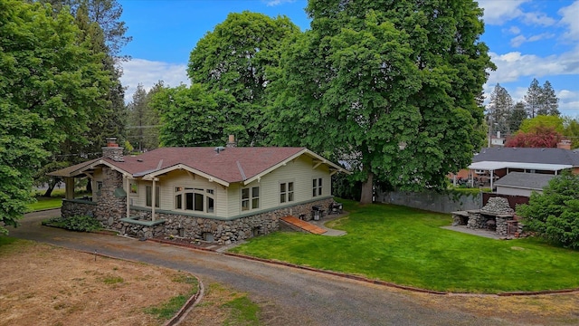 view of front facade with stone siding, a front lawn, and a chimney