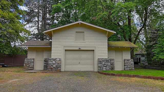 view of side of home with stone siding, a shingled roof, driveway, and a garage