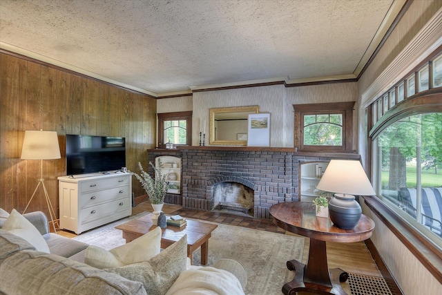 living area with ornamental molding, wooden walls, a brick fireplace, and a textured ceiling