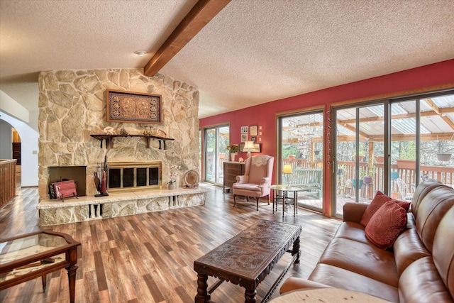 8410 E Columbia Park Dr, Spokane, WA 99212 - living room featuring a textured ceiling, arched walkways, wood finished floors, and a stone fireplace