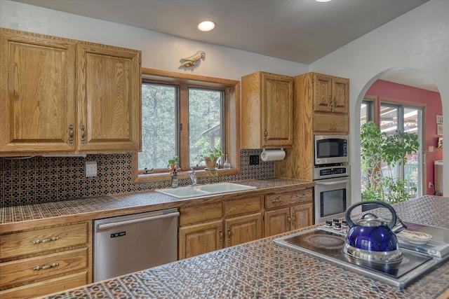 8410 E Columbia Park Dr, Spokane, WA 99212 - kitchen with appliances with stainless steel finishes, a sink, tasteful backsplash, arched walkways, and brown cabinets
