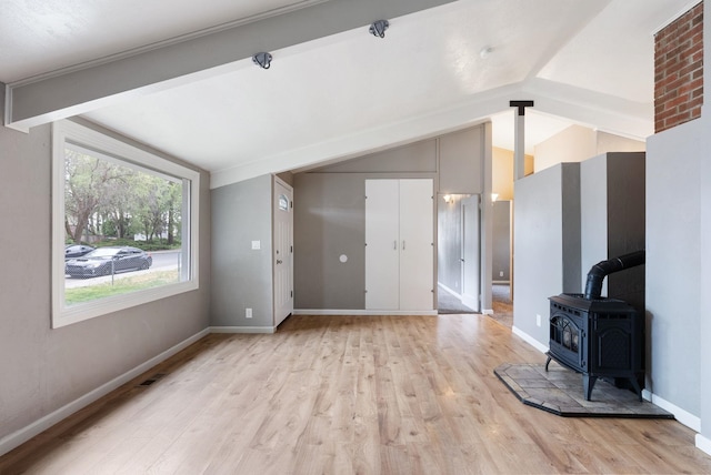 3123 E 36th Ave, Spokane, WA 99223 - unfurnished living room featuring lofted ceiling, light wood-style flooring, baseboards, and a wood stove