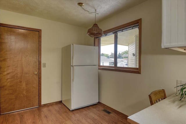 6923 N Hamilton St Unit 6923, Spokane, WA 99208 - kitchen featuring freestanding refrigerator, light wood finished floors, a textured ceiling, white cabinetry, and baseboards
