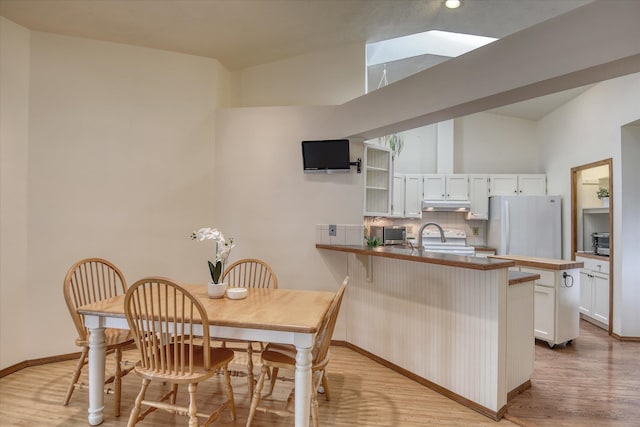 6923 N Hamilton St Unit 6923, Spokane, WA 99208 - kitchen featuring white appliances, a peninsula, under cabinet range hood, decorative backsplash, and light wood finished floors