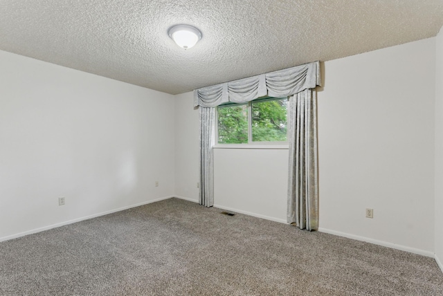 spare room featuring carpet, a textured ceiling, and baseboards