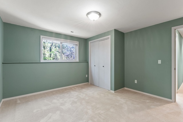 unfurnished bedroom featuring light carpet, a closet, and baseboards