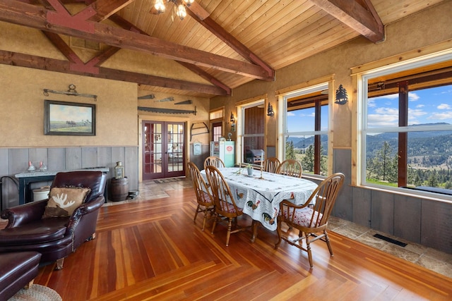 dining area featuring a wainscoted wall, french doors, a mountain view, wood ceiling, and wooden walls