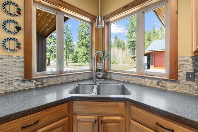 kitchen featuring a sink, dark countertops, healthy amount of natural light, and tasteful backsplash
