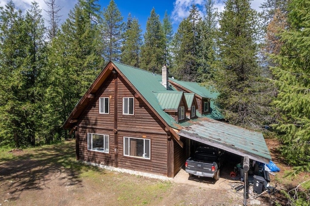 652 Penny Ln, Usk, WA 99180 - view of side of property with dirt driveway, a chimney, an attached carport, and metal roof