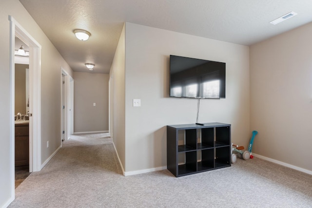 hall featuring carpet flooring, baseboards, a sink, and a textured ceiling