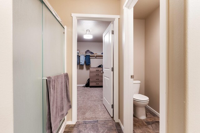 full bath with a stall shower, toilet, and a walk in closet