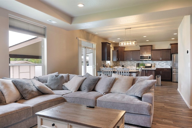 living room with plenty of natural light, dark wood finished floors, a chandelier, and recessed lighting