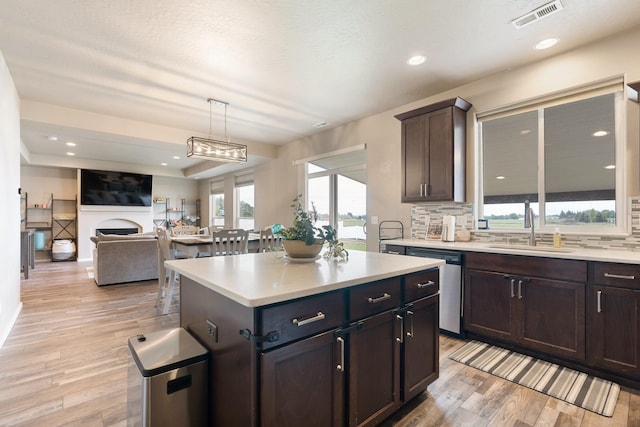 kitchen featuring a sink, light countertops, stainless steel dishwasher, light wood finished floors, and recessed lighting